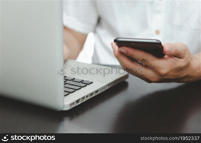 man hand using smart phoneand laptop on table at home, searching information browsing the internet on web, work from home.Business shopping online concept