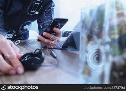 man hand using VOIP headset with digital tablet computer docking keyboard,smart phone,concept communication, it support, call center and customer service help desk with vase flower at foreground,virtual interface icons screen