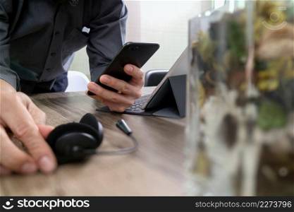 man hand using VOIP headset with digital tablet computer docking keyboard,smart phone,concept communication, it support, call center and customer service help desk with vase flower at foreground