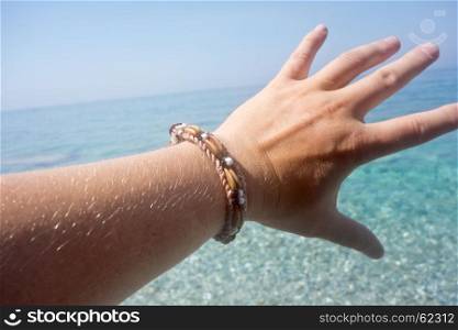 man hand with bracelet against beautiful sea, vacation concept