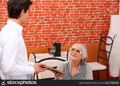 Man handing menu to old lady