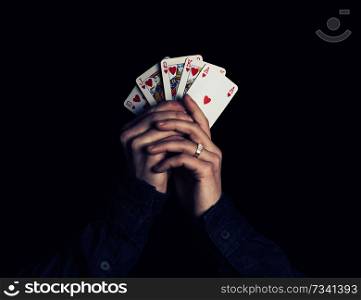 man hands holding playing cards with the strongest combination - royal flush