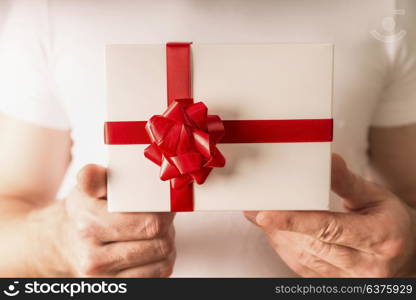Man hands holding white gift box with red ribbon , close up. Valentines day concept