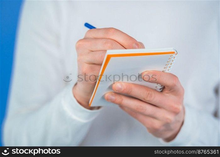 Man hands making notes in planner, caucasian guy holding pen. He writes future plans and to-do list in notebook for week or month. Keeping personal diary on blue studio background. High quality photo. Man hands making notes in planner, caucasian guy holding pen. He writes future plans and to-do list in notebook for week or month. Keeping personal diary on blue studio background.