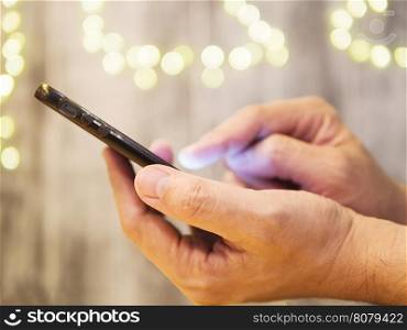 Man hands using / pushing mobile phone with light bokeh background