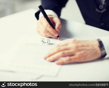 man hands with gambling dices signing contract. picture of man hands with gambling dices signing contract