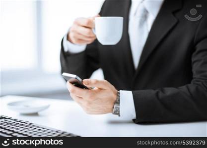 man hands with keyboard holding smartphone and drinking coffee