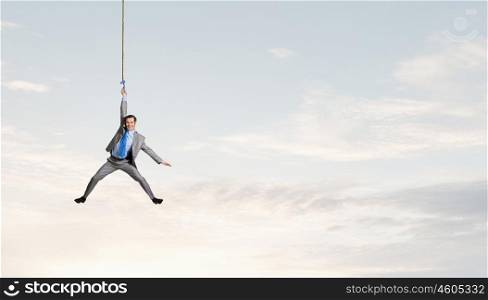 Man hang on rope. Young businessman hanging on rope high in sky