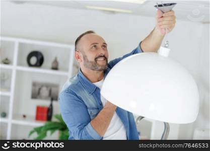 man hanging a lamp at home