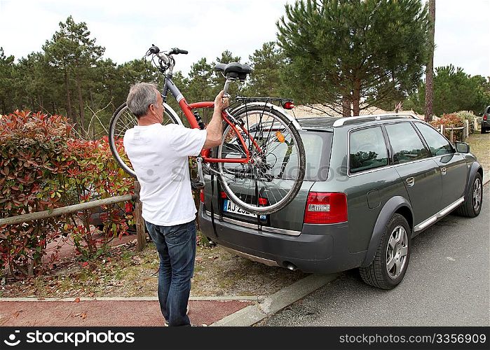Man hanging bicycle on bike carrier