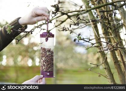 Man Hanging Bird Feeder In Garden