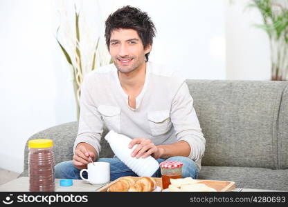 Man having breakfast on sofa