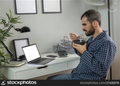 man having breakfast while working from home