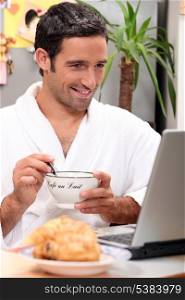 Man having breakfast with computer