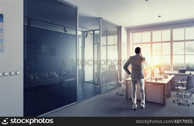 Man having business talk mixed media. Man boss having mobile phone conversation while standing in modern office