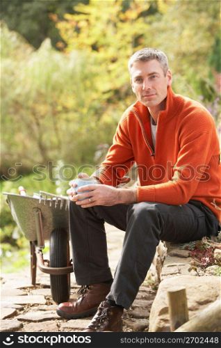 Man Having Coffee Break Whilst Working Outdoors In Garden