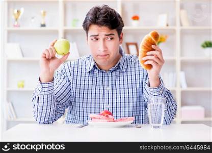 Man having dilemma between healthy food and bread in dieting concept. Man having dilemma between healthy food and bread in dieting con