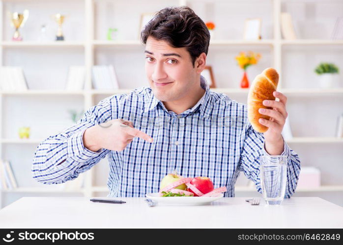 Man having dilemma between healthy food and bread in dieting concept. Man having dilemma between healthy food and bread in dieting con