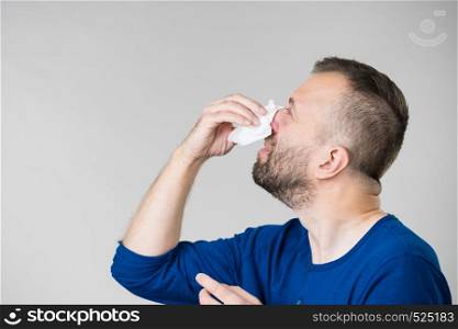 Man having flu, sneezing into hygienic tissue. Guy being sick, allergic blowing his nose.. Man blowing nose