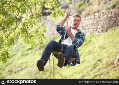Man Having Fun On Woodland Swing In Autumn
