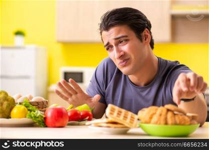 Man having hard choice between healthy and unhealthy food