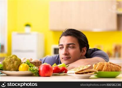 Man having hard choice between healthy and unhealthy food. The man having hard choice between healthy and unhealthy food