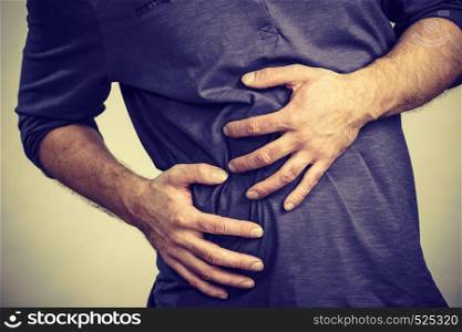 Man having huge stomach pain holding his belly feeling very unwell. Guy being sick and unhealthy.. Man feeling stomach ache pain