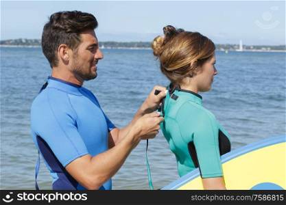 man helping girlfriend with wetsuit