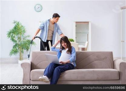 Man helping pregnant wife in cleaning 