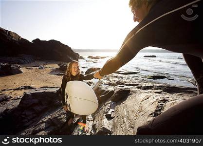 Man helping woman with surfboard