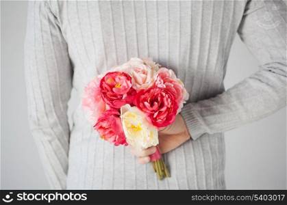 man hiding bouquet of flowers behind his back.