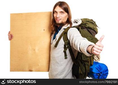 Man hiker backpacker with blank wood copy space ad. Man tourist backpacker holding blank wood plank copy space. Young guy hitchhiking with thumb up gesture. Male hiker backpacking.