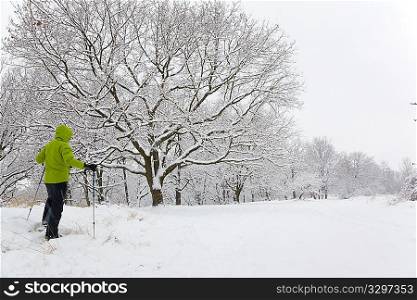 Man hiking on snowshoes in winter forest during a blizzard. Horizontal frame.
