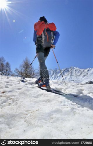 man hiking with ski touring in snowy mountain under sunny sky