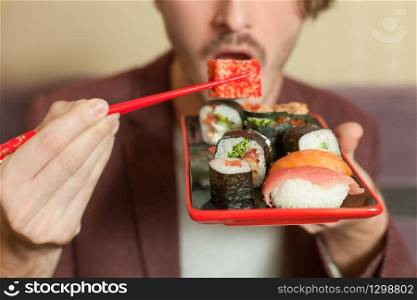 Man hold chopsticks in hand. Chopsticks with sushi roll.. Man hold chopsticks in hand.