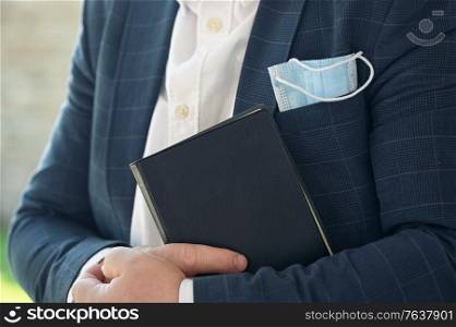 Man Hold Holy Bible with a medical mask sticks out of a pocket