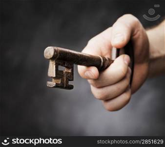 Man holding a big antique key in his hand. Very short depth-of-field.