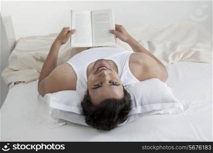 Man holding a book while lying in bed
