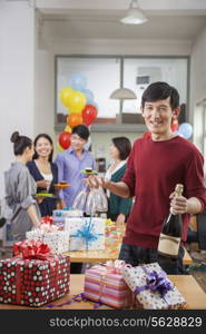 Man Holding A Bottle Of Champagne and Glasses At Office Party