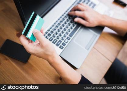 Man holding a credit card and typing. On-line shopping on the internet using a laptop