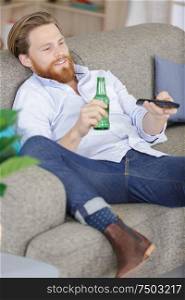 man holding a empty beer bottle while watching tv