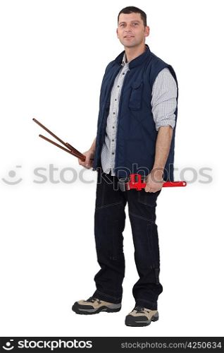 Man holding a pipe wrench and copper pipes