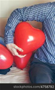 Man holding a red heart shaped balloon
