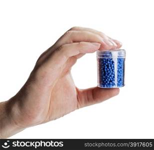 Man holding a small container with blue plastic granules, used for manufacturing.