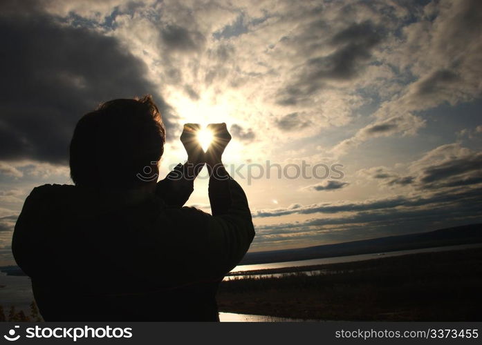 man holding a sun in his hands against the sky