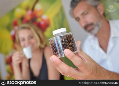 Man holding a transparent jar of coffee beans