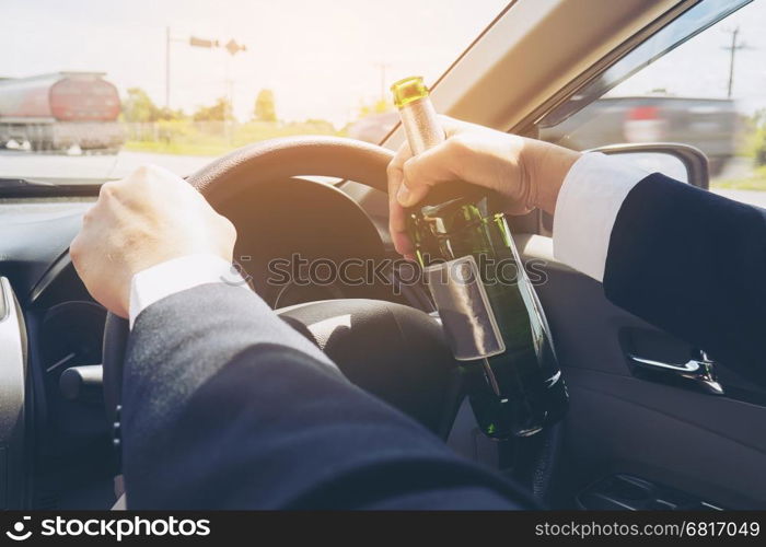 Man holding beer bottle while driving a car