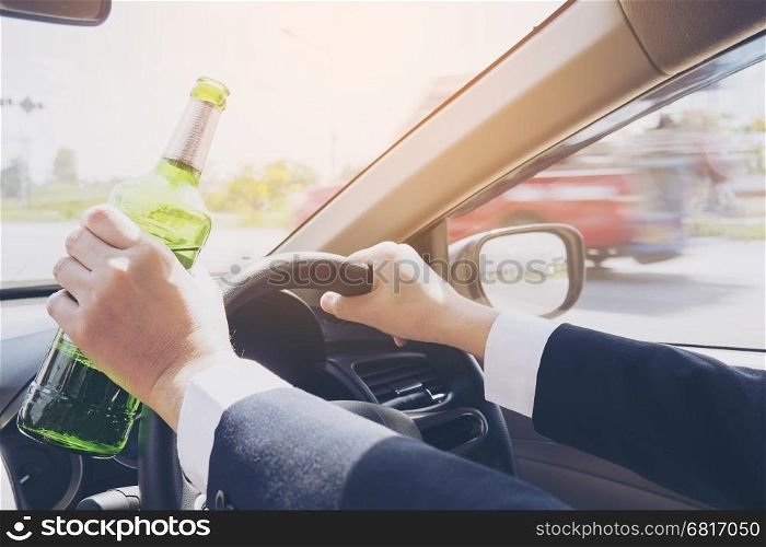 Man holding beer bottle while driving a car
