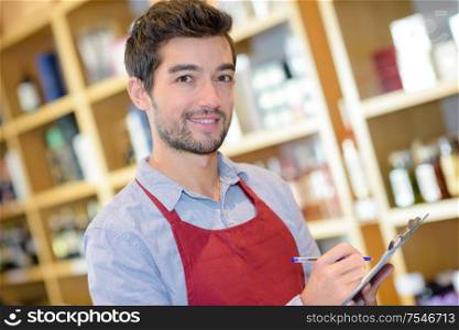 man holding bottle of wine and writing on clipboard