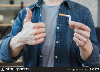 man holding broken cigarette showing thumb up gesture